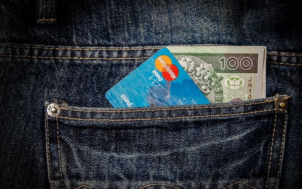 Scheckkarte und Geld blitzen aus der Hosentasche