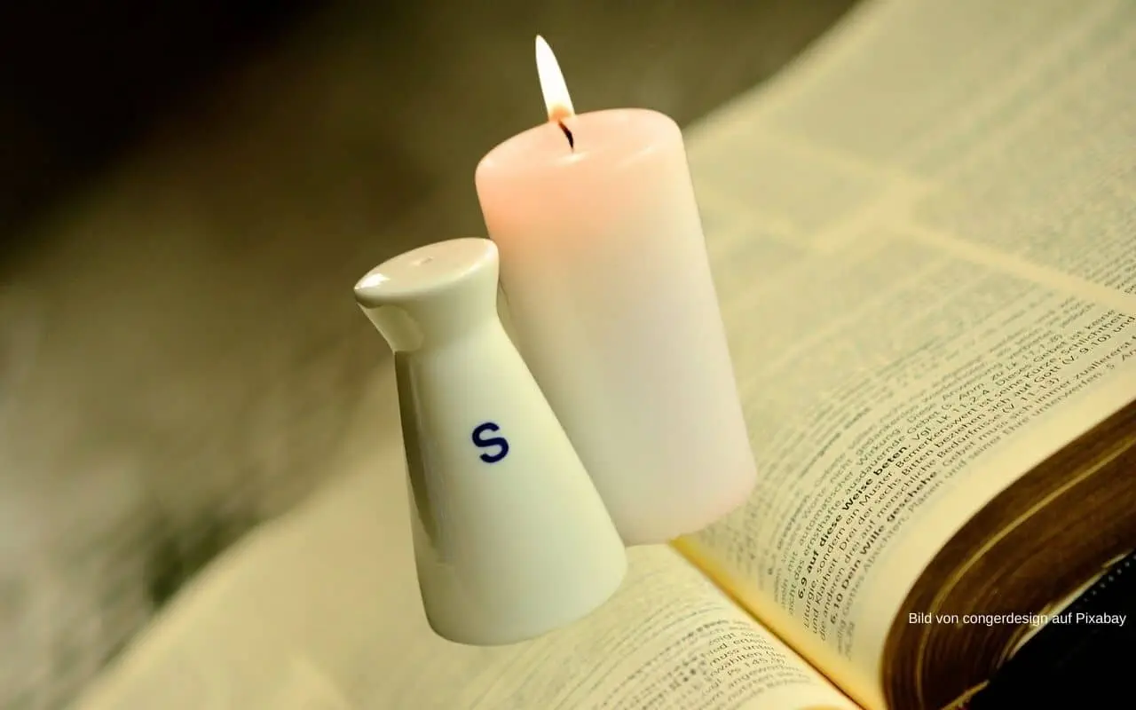 Kerze und Salz stehen auf der aufgeschlagenen Bibel